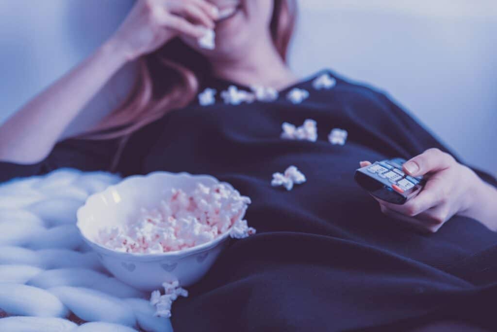 Young woman eating popcorn on the couch