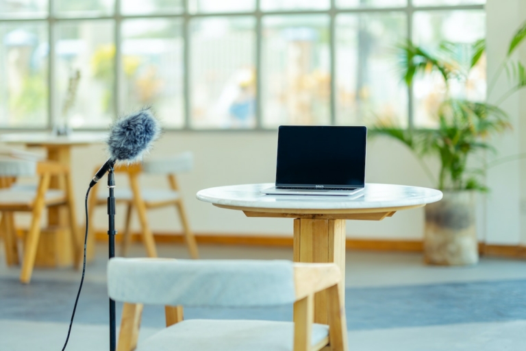 a table with a laptop and professional microphone next to it to record something